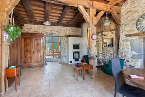 A rustic interior with exposed wooden beams, a stone wall, a wooden cabinet, a table with chairs, and a clock. - Country House "Domaine Baraque" with Mountain View, Wi-Fi, and Air Conditioning (Pouillon)