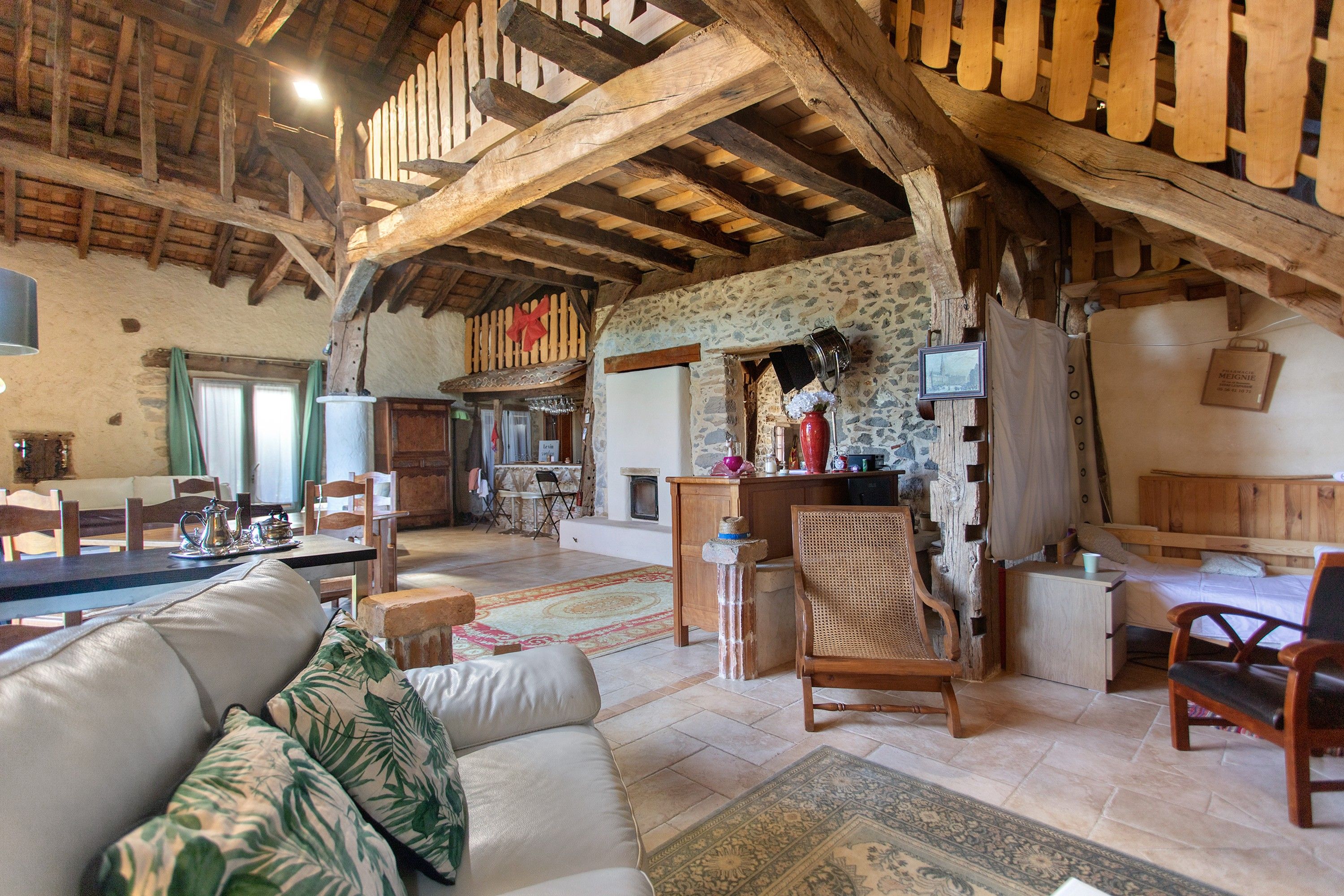 Ein rustikaler Innenraum mit freiliegenden Holzbalken, einer Steinwand, einem Kamin und einem Essbereich.