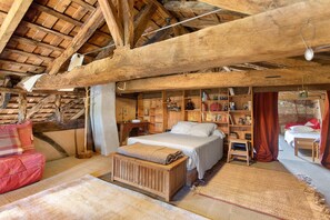 Une chambre à coucher rustique avec un lit en bois, un petit bureau et une bibliothèque remplie de livres et d’objets décoratifs.