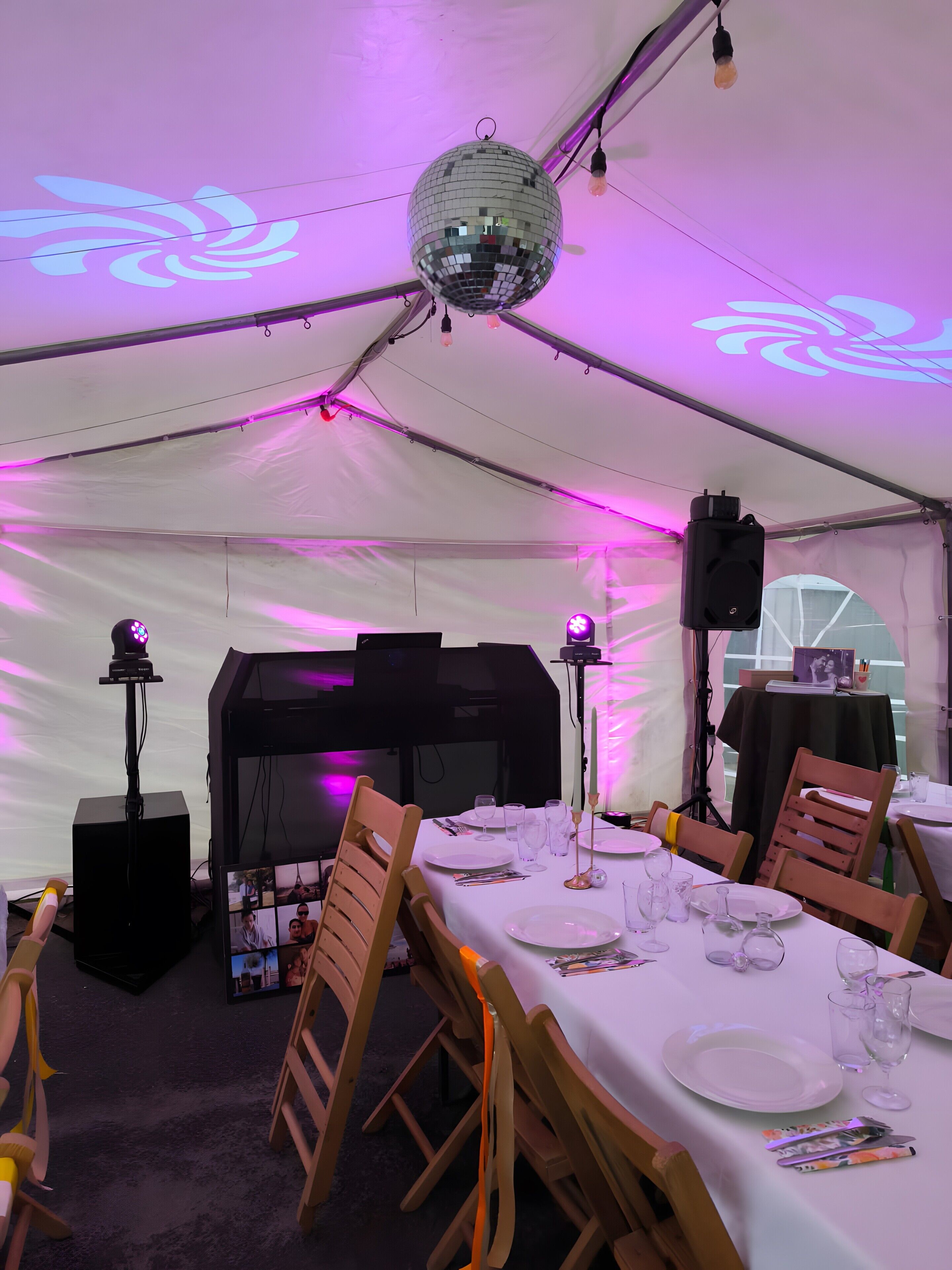 Un espace de restauration aménagé sous une tente, avec des tables dressées pour le repas, une boule à facettes et un système de sonorisation.