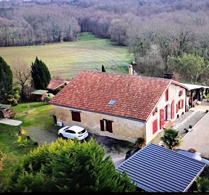 A house with a red-tiled roof, a white car parked in front, and a solar panel on the roof. - Country House "Domaine Baraque" with Mountain View, Wi-Fi, and Air Conditioning (Pouillon)