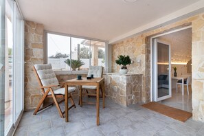 A stone-walled room with a dining table, chairs, and a potted plant.
