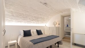 Una camera da letto con un letto, un comodino, una lampada e vista sul bagno.