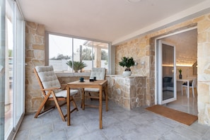 A modern interior with stone walls, a glass door leading to an outdoor area, and a dining table with chairs.