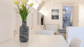 A modern interior with a marble vase on a white table, a white chair, and a ceiling with a textured pattern.