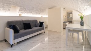 Ein modernes Interieur mit einem grauen Sofa, einem weißen Esstisch und einem Blumenstrauß.