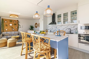 Une cuisine moderne dotée d’un îlot central, de meubles blancs et d’un pare-feu en marbre.
