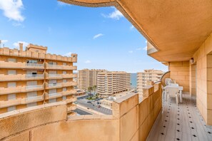 A high-rise building with multiple balconies, a clear sky, and a view of other buildings.