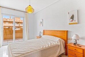 Makuuhuoneessa on sänky, yöpöydät, lamppu, taulu ja näkymä, joka avautuu liukuoven kautta.