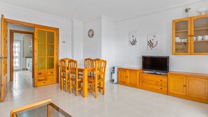 A dining area with a wooden table and chairs, a television, and a cabinet with glass doors.