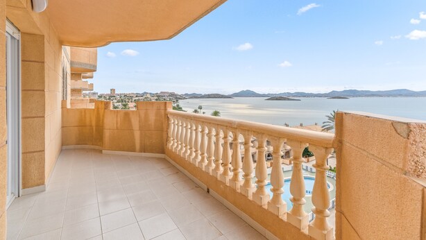 A balcony with a view of a beach and mountains.
