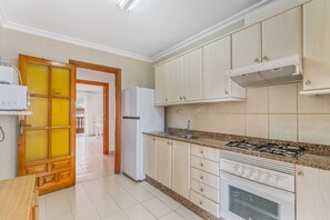 Una cocina con estufa a gas, horno y refrigerador.