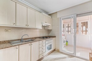 A kitchen with a sink, stove, oven, and cabinets.