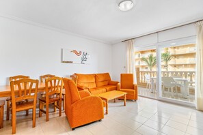 A living room with a sofa, chairs, a coffee table, and a dining table.