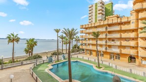 A hotel with a pool, palm trees, and a view of the sea. - Apartment 'Castillo De Mar F3 Torre Sur 2a' with Sea View, Shared Pool and Wi-Fi (La Manga del Mar Menor)