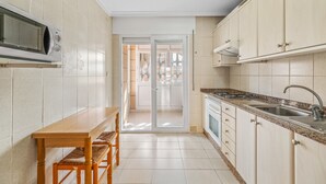 Keittiössä on mikroaaltouuni, pesuallas, kaappeja sekä pöytä ja tuolit.