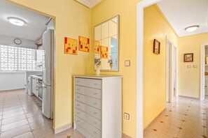 Un couloir avec une commode blanche, un miroir et des œuvres d’art murales.