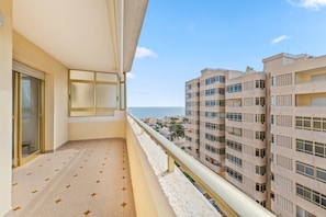 A balcony with a patterned floor, a sliding glass door, and a view of adjacent buildings.