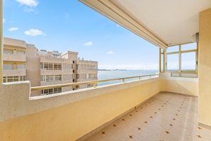 A balcony with a clear view of the sea and adjacent buildings.