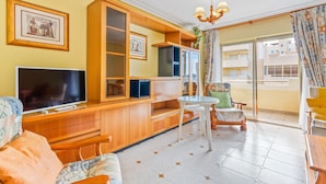 A living room with a TV, wooden cabinets, a small table, and a sofa.