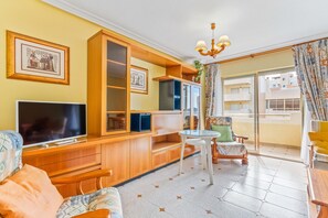 A living room with a TV, wooden cabinets, a small table, and a sofa.