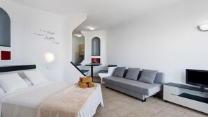 Une chambre d’hôtel moderne équipée d’un lit, d’un canapé, d’une télévision et d’une citation inspirante affichée sur le mur.
