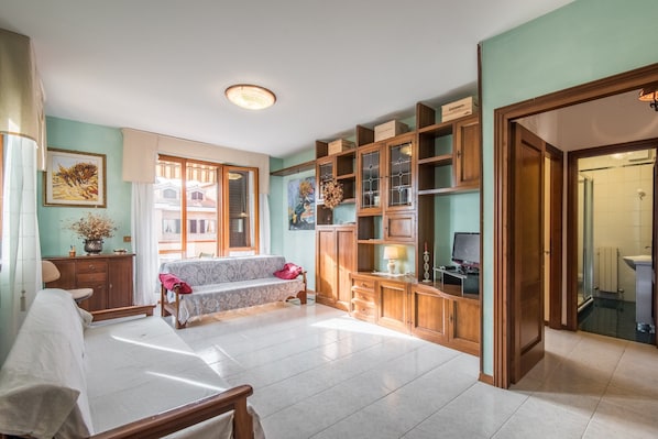 Un vaste espace de vie comprenant un canapé, un téléviseur, des meubles en bois et une grande fenêtre.