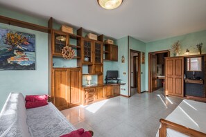Un salon avec un canapé, un téléviseur, des meubles en bois et un tableau accroché au mur.