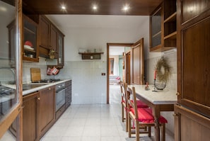 Une cuisine avec des meubles en bois, une cuisinière et un coin repas avec des chaises.