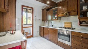 Una cocina con armarios de madera, una estufa a gas, un horno y un ventanal.