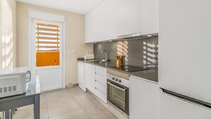A modern kitchen with white cabinets, a stainless steel range, a built-in oven, and a window with blinds. - Apartment 'Playa Principe Esc 10' with Sea View, Wi-Fi and Air Conditioning (La Manga del Mar Menor)