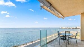 A balcony with a glass railing overlooking a coastal road and the sea. - Apartment 'Playa Principe Esc 10' with Sea View, Wi-Fi and Air Conditioning (La Manga del Mar Menor)