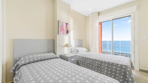 A bedroom with two beds, a nightstand, a lamp, and a painting on the wall. - Apartment 'Playa Principe Esc 10' with Sea View, Wi-Fi and Air Conditioning (La Manga del Mar Menor)