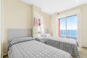 A bedroom with two beds, a nightstand, a lamp, and a painting on the wall.