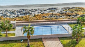 A swimming pool with a view of the beach and palm trees. - Apartment 'Playa Principe Esc 10' with Sea View, Wi-Fi and Air Conditioning (La Manga del Mar Menor)