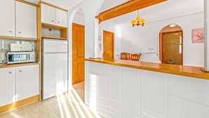 Eine moderne Küche mit weißen Schränken, einer Holz Arbeitsplatte, einer eingebauten Mikrowelle und einer Pendelleuchte.