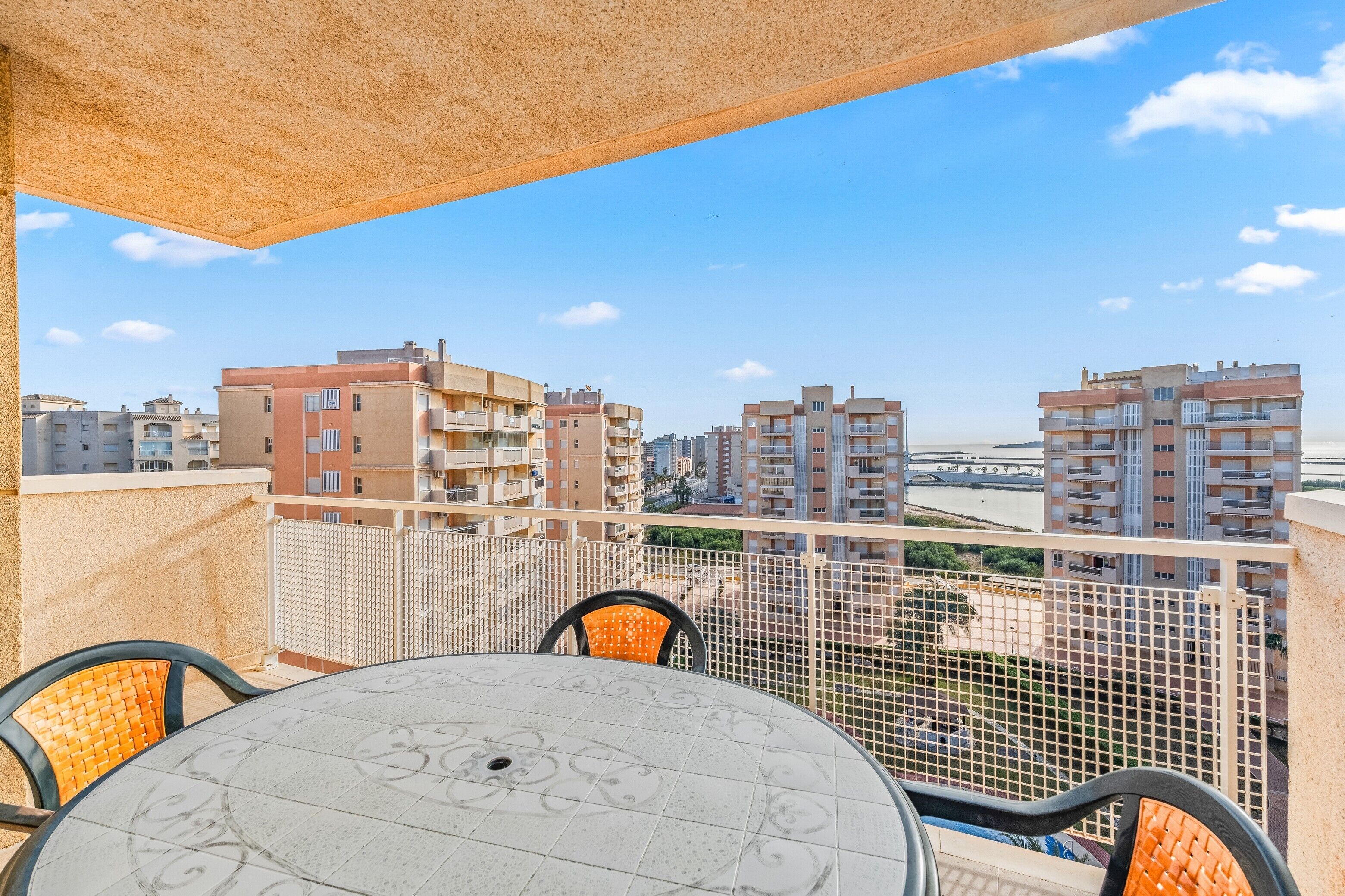 Un balcon avec une table et des chaises, donnant sur un paysage urbain composé de nombreux immeubles.