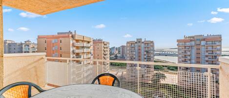 Un balcon avec une table et des chaises, donnant sur un paysage urbain composé de nombreux immeubles.