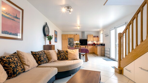 A modern living room with a sofa, coffee table, and a dining area with a table and chairs. - Holiday Home 'Maison Vue Mer 150m De La Plage' with Sea View, Private Terrace and Wi-Fi (Trégunc)