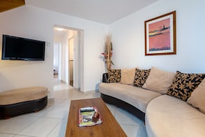 Un salón con sofá, una mesa de centro, televisor y un cuadro en la pared.