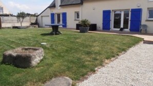 A building with a sloped roof, a gravel driveway, and a grassy lawn. - Holiday Home 'Maison Vue Mer 150m De La Plage' with Sea View, Private Terrace and Wi-Fi (Trégunc)