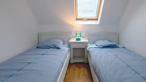 A small, single-room with two beds, a nightstand with a lamp, and a skylight. - Holiday Home 'Maison Vue Mer 150m De La Plage' with Sea View, Private Terrace and Wi-Fi (Trégunc)