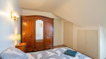 A bedroom with a bed, a wardrobe, a nightstand, and a wall-mounted light fixture.