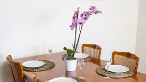 A dining table with four chairs, a potted orchid, and a white vase. - Holiday Apartment "Gîte Le Lot " with Wi-Fi (ESPALION)