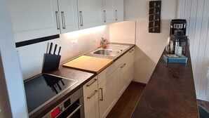 A modern kitchen with white cabinets, a black countertop, and stainless steel appliances. - Greppons N 012 - MOUNTAIN apartment 6 pers (Veysonnaz)