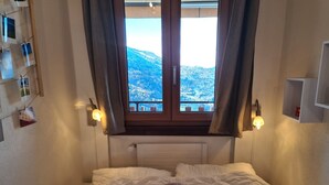 A bedroom with a bed, a window with curtains, and a view of a snowy landscape. - Greppons N 012 - MOUNTAIN apartment 6 pers (Veysonnaz)