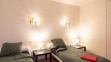 Une chambre d’hôtel avec deux lits, deux tables de chevet, des appliques murales et une porte.