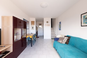 Un apartamento moderno con comedor, sofá y una escalera que lleva a un piso superior.