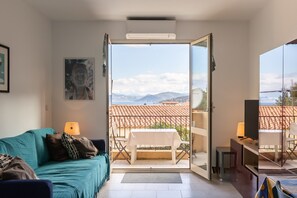 Ein Wohnzimmer mit einer Couch, einem Tisch und einem Balkon mit Bergblick.