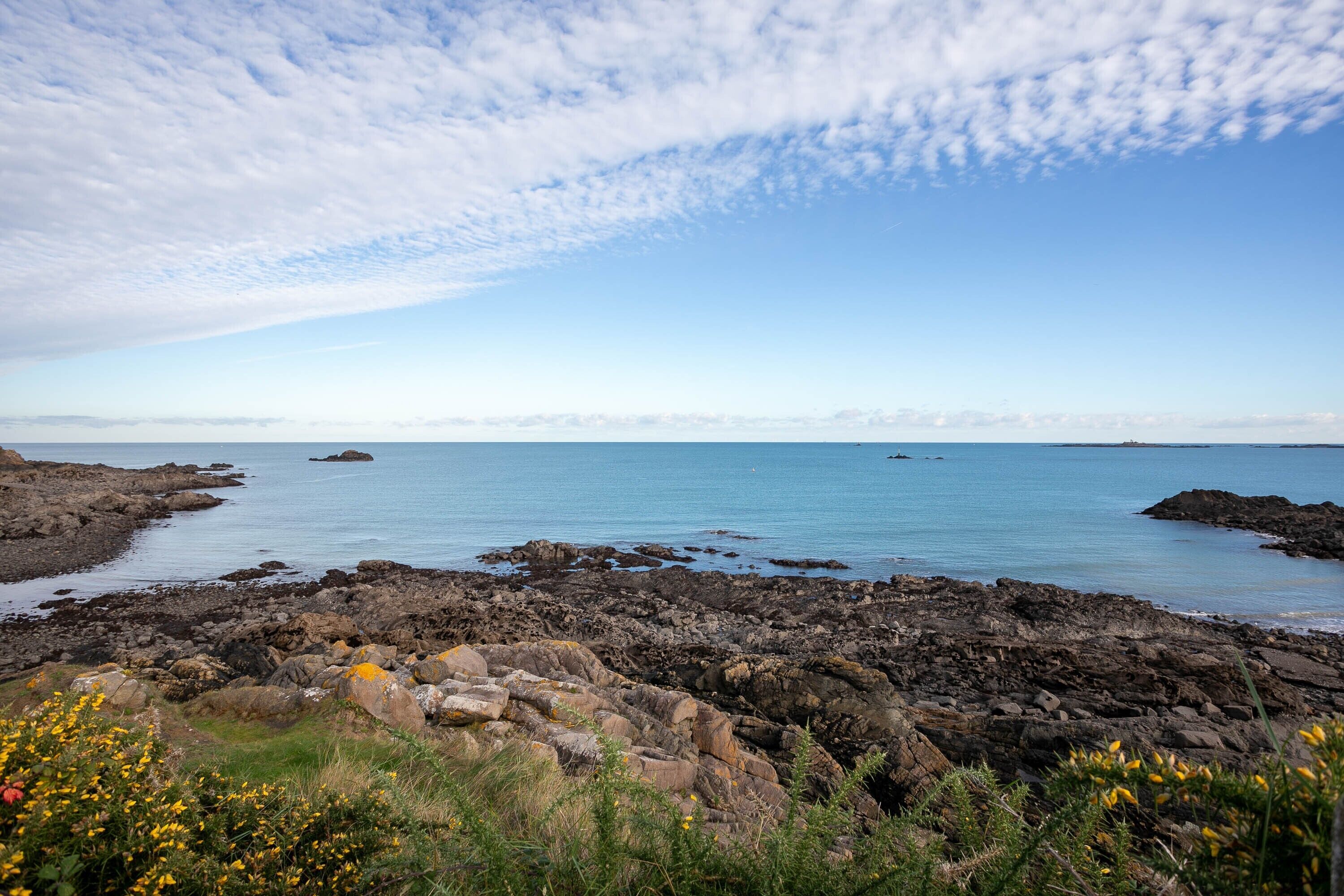 A rocky coastal landscape with clear skies and calm waters.